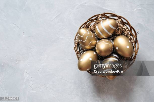 easter decorative eggs in gold color with a pattern in a basket on a gray background - easter eggs basket bildbanksfoton och bilder