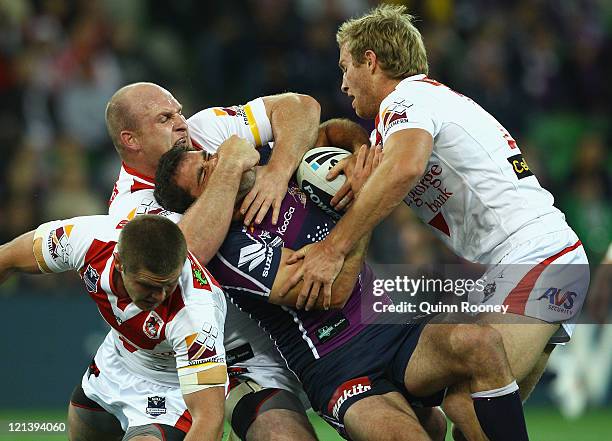 Cameron Smith of the Storm is tackled by Michael Weyman and Matt Prior of the Dragons during the round 24 NRL match between the Melbourne Storm and...