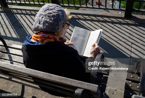 Woman reads from the book A Very Stable Genius: Donald J. Trump's Testing of America by Philip Rucker and Carol Leonnig along the Brooklyn Heights...