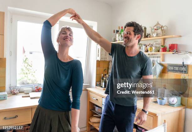 happy couple dancing in kitchen at home - pareja de mediana edad fotografías e imágenes de stock