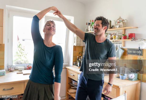 happy couple dancing in kitchen at home - couple dancing at home stockfoto's en -beelden
