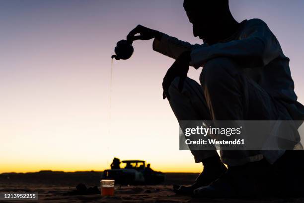 silhouette of man preparing tea in sahara desert, tindouf, algeria - algerian people stock pictures, royalty-free photos & images