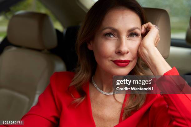 portrait of pensive mature woman in car - red dress stock-fotos und bilder