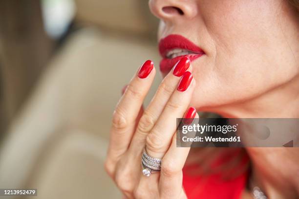 crop view of mature woman with red lips and nails - red nail polish stock-fotos und bilder