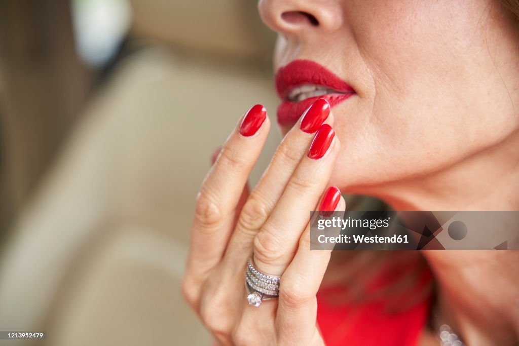 Crop view of mature woman with red lips and nails