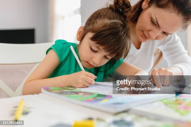mother helping daughters with homework - workbook stock pictures, royalty-free photos & images