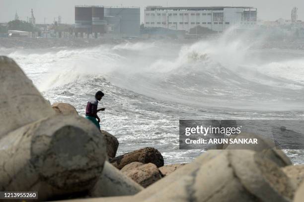 Man looks out as waves hit a breakwater at Kasimedu fishing harbour in Chennai on May 19 as Cyclone Amphan barrels towards India's eastern coast. -...