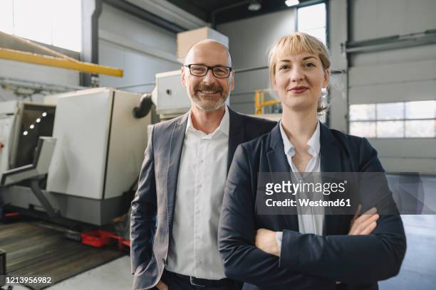 portrait of confident businessman and businesswoman in a factory - industrie porträt stock-fotos und bilder