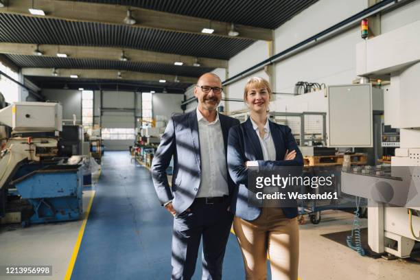 portrait of confident businessman and businesswoman in a factory - lead stock-fotos und bilder