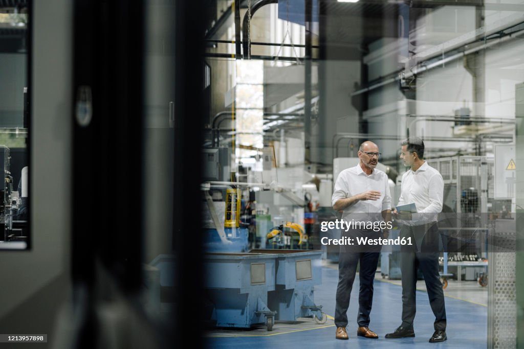 Two businessmen talking in a factory