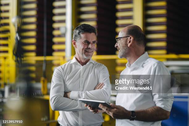 two businessmen using tablet in a factory - portrait business partners stock-fotos und bilder