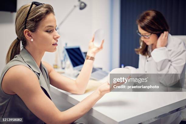 una mujer joven está eligiendo implantes mamarios en la clínica de tratamiento de belleza - best bosom fotografías e imágenes de stock