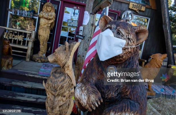 Chainsaw carved bear wears a facemark at Rustic Furniture, which is temporarily closed due to coronavirus restrictions on Thursday, May 14, 2020 in...