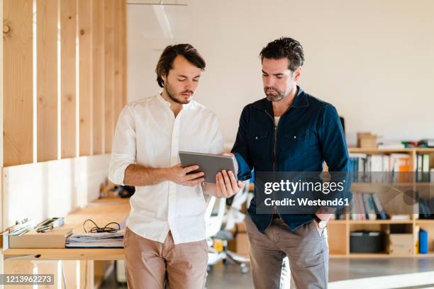 two businessmen with tablet talking in wooden open-plan office - open space office stock-fotos und bilder