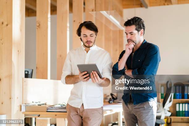 two businessmen with tablet talking in wooden open-plan office - open day 2 stock-fotos und bilder