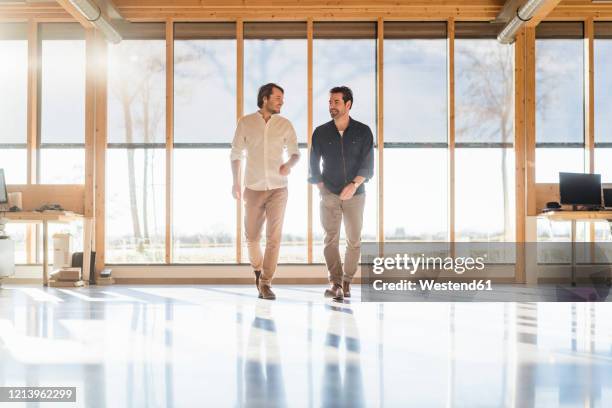 two businessmen talking in wooden open-plan office - bright light open interior stock-fotos und bilder