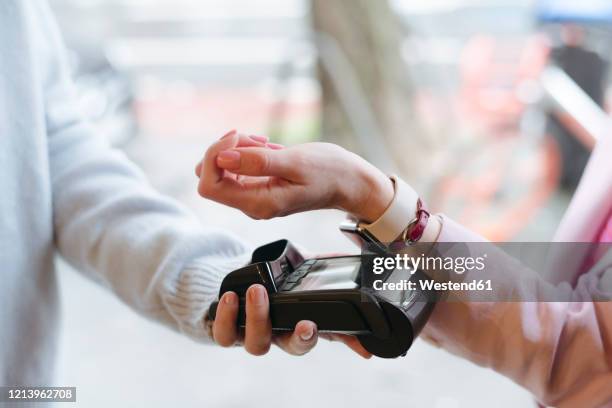 hand of woman, paying cashless at pos terminal with her smartwatch - watch payment stock pictures, royalty-free photos & images