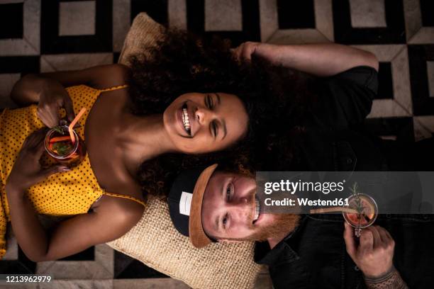 portrait of happy couple lying on the floor drinking fresh ice tea - eistee stock-fotos und bilder