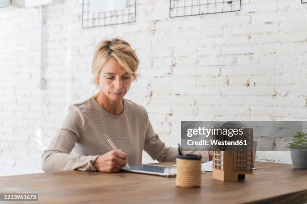 mature woman working at desk in architectural office - pen mockup stock-fotos und bilder