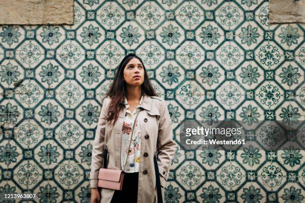 portugal, lisbon, young traveller looking up and standing at a wall with typical portuguese tiles - azulejos foto e immagini stock