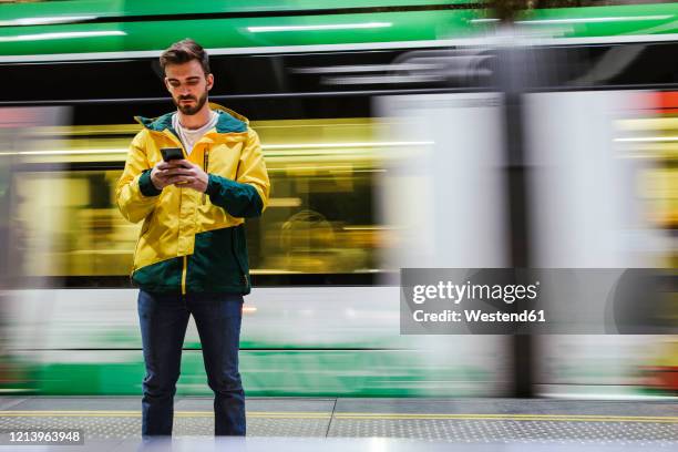 man using cell phone on subway station - 經過 個照片及圖片檔