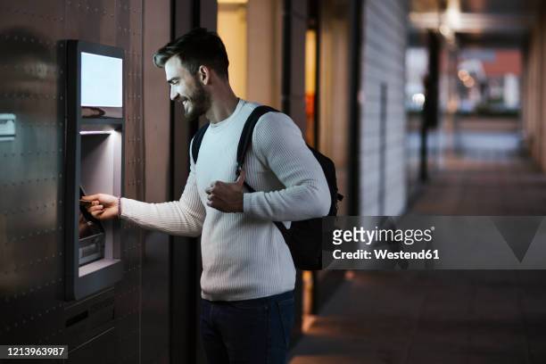 man withdrawing money at an atm in the city - dab photos et images de collection