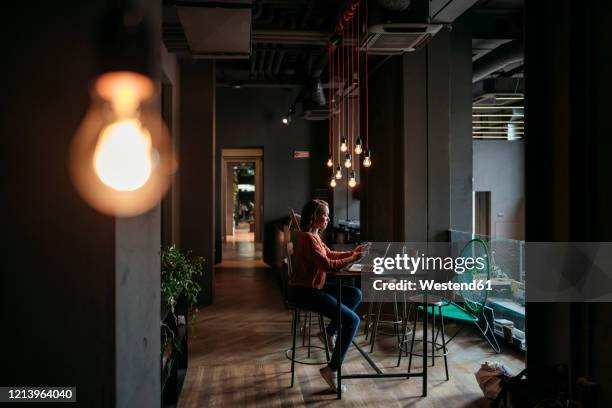 young woman using laptop and smartphone in a cafe - smartphones dangling stock pictures, royalty-free photos & images