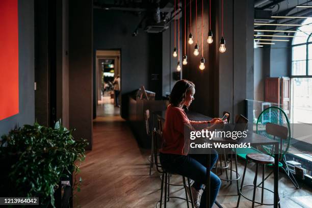 young woman using laptop and smartphone in a cafe - sgabello foto e immagini stock