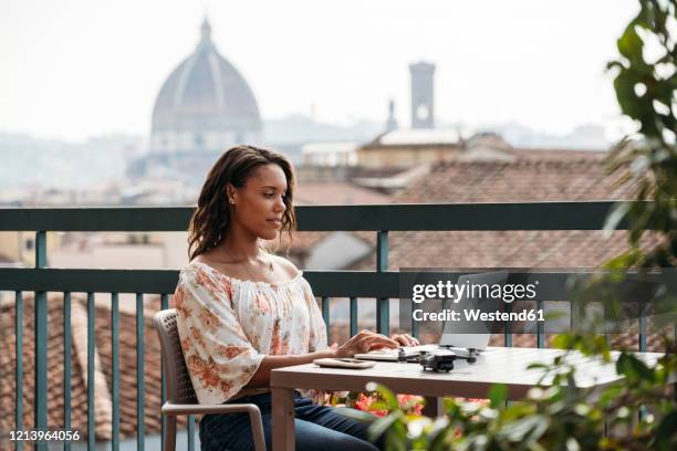 young woman using laptop on a balcony in florence, italy - famous women in history stockfoto's en -beelden