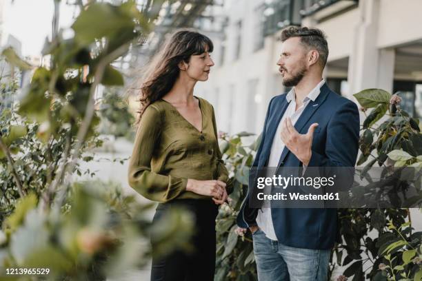 businessman and casual businesswoman talking outdoors - looking at art stock-fotos und bilder