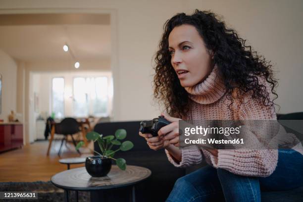 woman sitting on couch, having fun, playing with a gaming console - pre game stockfoto's en -beelden