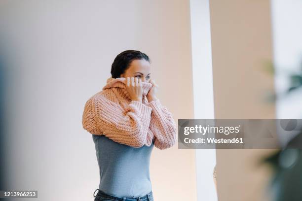 woman putting on cozy sweater - sweater stock pictures, royalty-free photos & images