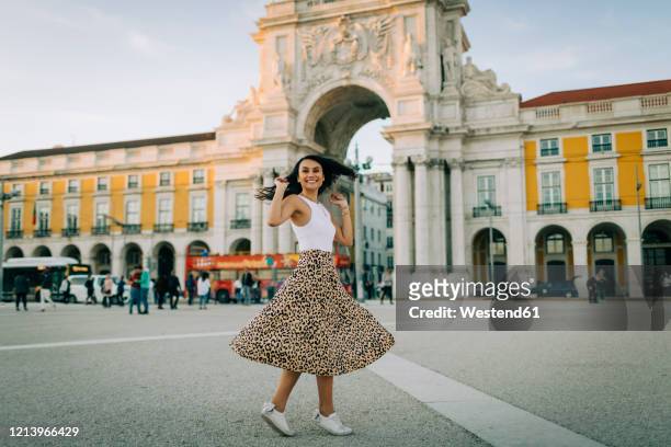 happy young woman dancing in the city, lisbon, portugal - comercio stock-fotos und bilder