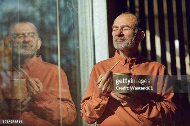 relaxed businessman having sustainable lunch in his office - senior men eating stock pictures, royalty-free photos & images