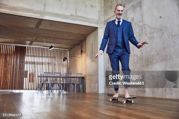 senior businessman skateboarding in his office - excentrique photos et images de collection