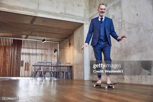 senior businessman skateboarding in his office - eccentric ストックフォトと画像