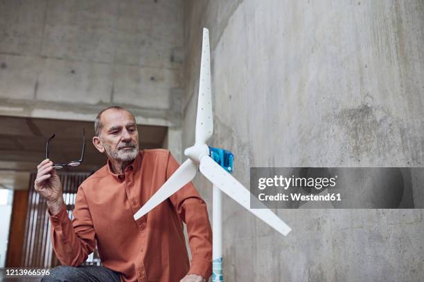 senior engineer working on wind energy solutions, looking at wind turbine - anti ageing stockfoto's en -beelden