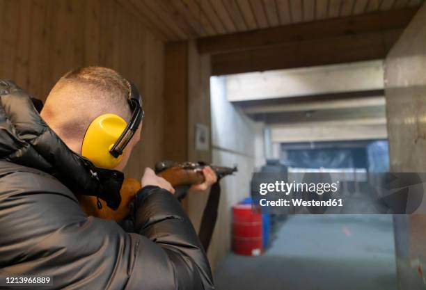 young man aiming with a gun in shooting range - kalashnikov fotografías e imágenes de stock