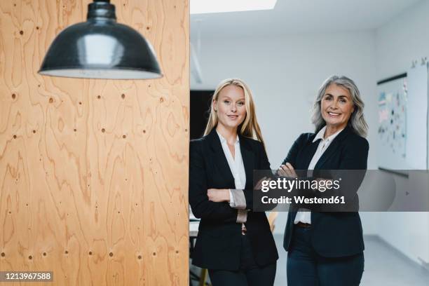 portrait of confident mature and young businesswoman in loft office - successor stockfoto's en -beelden