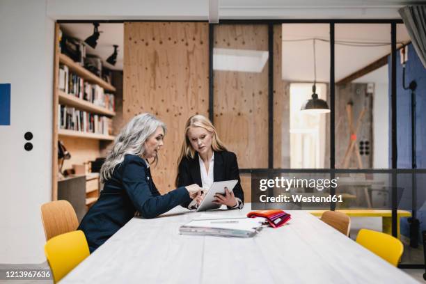 mature and young businesswoman using tablet in loft office - successor stockfoto's en -beelden