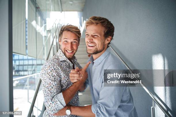 portrait of two happy young businessmen shaking hands - two guys laughing stock pictures, royalty-free photos & images