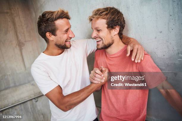 two happy friends embracing and shaking hands - passer le bras autour photos et images de collection