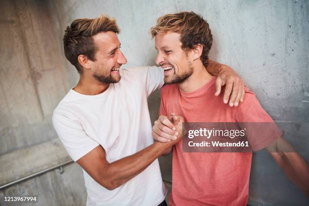 two happy friends embracing and shaking hands - arms around stockfoto's en -beelden