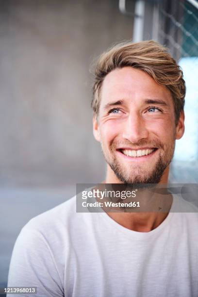 portrait of smiling young man wearing white t-shirt - barba peluria del viso foto e immagini stock