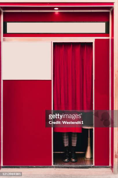 woman wearing red coat and boots standing behind curtain in a photo booth - photomaton - fotografias e filmes do acervo