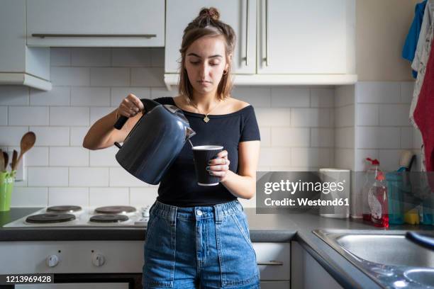 young woman preparing an instant coffee in kitchen at home - making coffee stock pictures, royalty-free photos & images