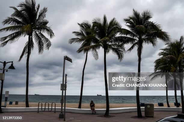 Girl sits on the pavement on Fort Lauderdale Beach Boulevard in Fort Lauderdale,Florida on May 18, 2020. - South Florida begins a gradual reopening...