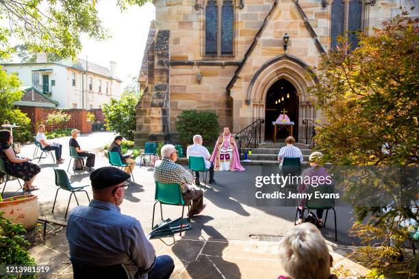 Father James Collins holds a service in the yard of St Paul's Anglican Church in Burwood with seating observant of social distancing on March 22,...