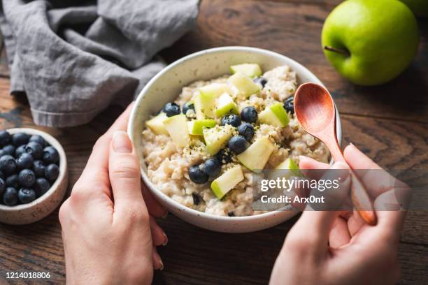 bowl of oatmeal porridge with apple and blueberry - fiocchi di avena foto e immagini stock