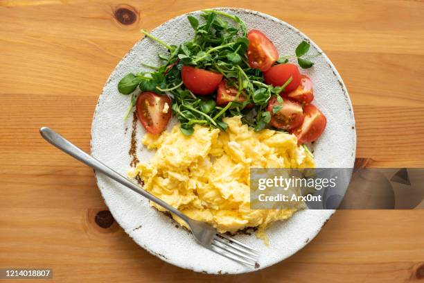 scrambled eggs with tomato arugula salad - roerei stockfoto's en -beelden